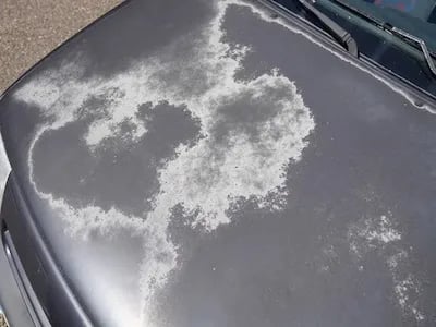 Frost and snow patterns on car hood showing paint damage