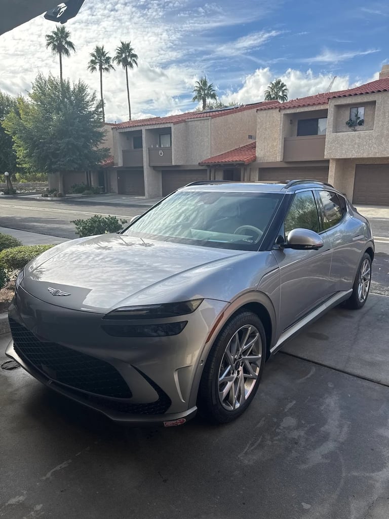 Silver Chevrolet Blazer EV parked in a driveway with palm trees and residential townhouses in the background