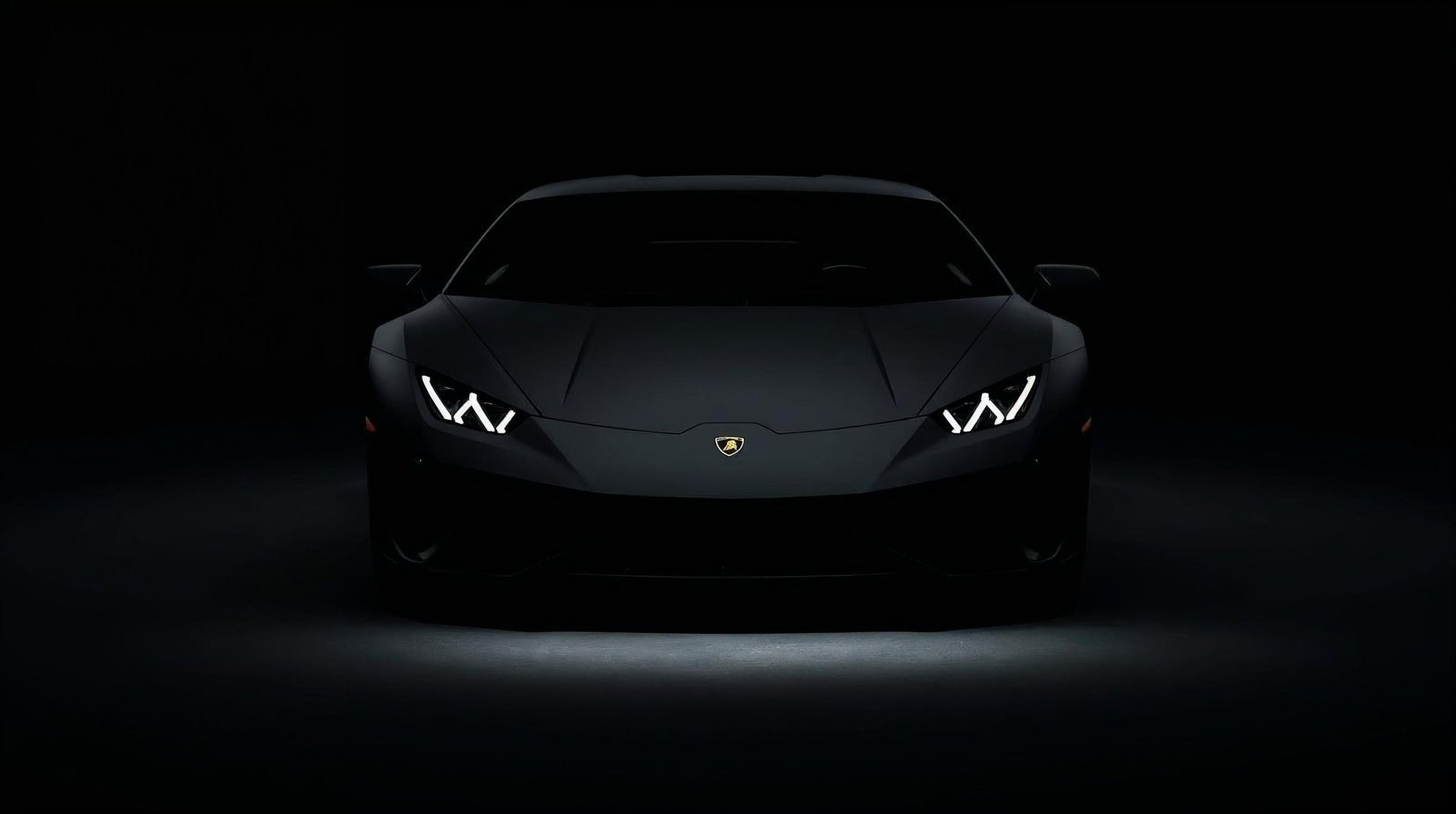 Front view of a sleek black Lamborghini sports car with angular LED headlights against a dark background