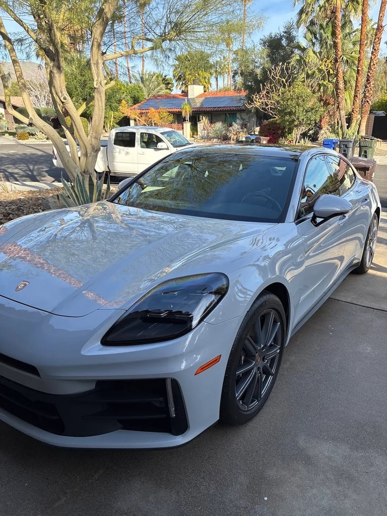 White sports car parked on street with house and trees in background